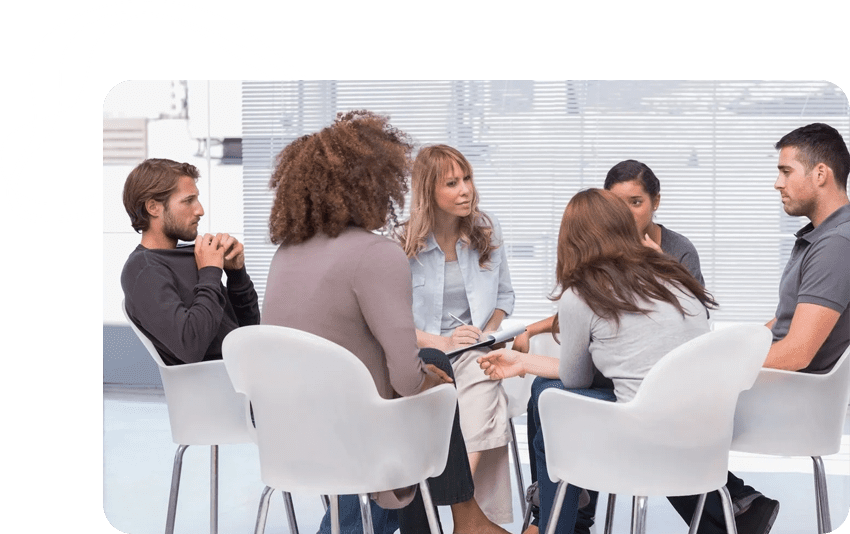 A group of people sitting in chairs talking.