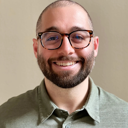 A man with glasses smiling for the camera.