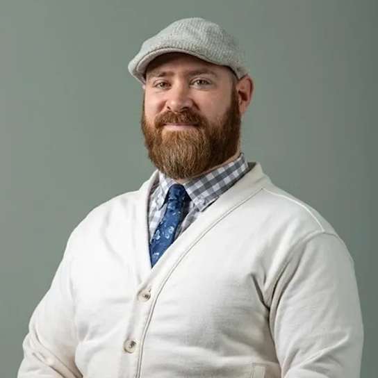 A man with a beard wearing a hat and tie.